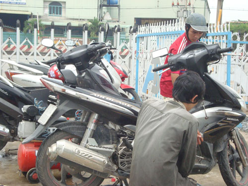 Thợ sửa xe máy đang lau bugi, khởi động xe máy cho dân
