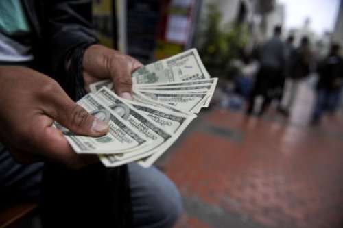 Một nhà buông ngoại tệ đến tiền trên đường phố - Ảnh: AFP