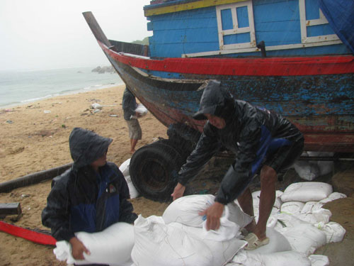 Người dân xã Nhơn Hải (TP.Quy Nhơn) kéo tàu lên bờ buộc chặt, dùng bao tải cát chắn phía dưới đáy để bảo đảm an toàn