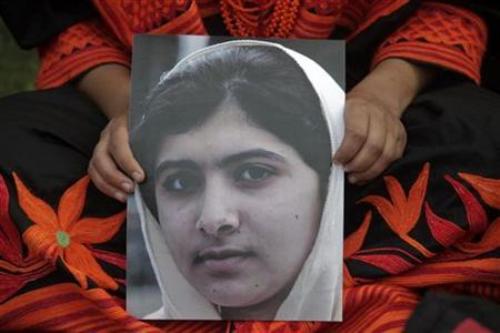 Người biểu tình cầm ảnh cô bé dũng cảm Malala Yousufzai - Ảnh: Reuters