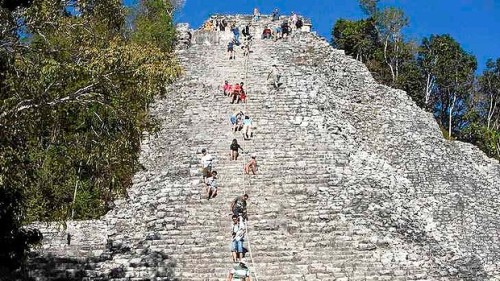 Tourists climb the Maya pyramid of Nohoch Mul at the archaeological site of Coba