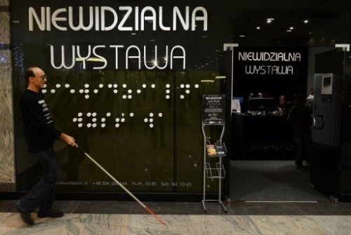 Một người hướng dẫn khiếm thị bước vào triển lãm Vô hình ở thủ đô Warsaw của Ba Lan - Ảnh: AFP