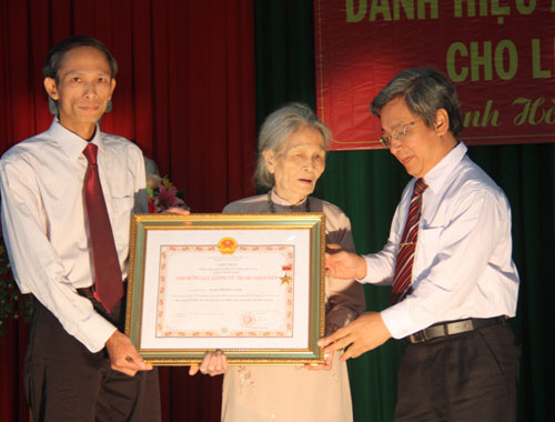 Ông Lê Xuân Thân, Phó Chủ tịch UBND tỉnh Khánh Hòa (phải) trao danh hiệu Anh hùng LLVTND truy tặng liệt sĩ Đặng Thị Kim cho thân nhân gia đình
