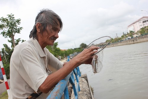 Ông Phú (64 tuổi) cũng mang vợt ra vớt khu vực trước nhà cho vui