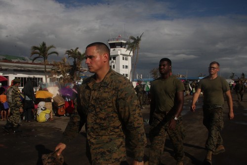 Một nhóm binh sĩ tình nguyện Mỹ đi ngang qua những người di tản đang ngồi đợi máy bay