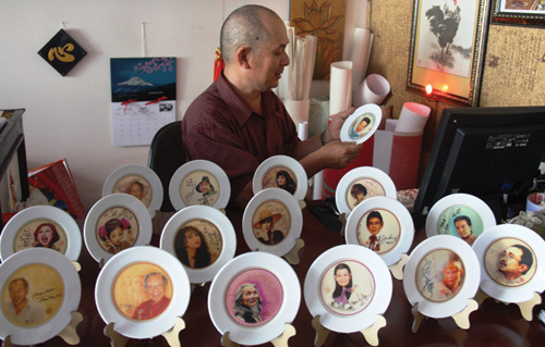 Anh Trần Quốc Ẩn bên những đĩa sứ có họa chân dung và chữ ký các văn nghệ sĩ nổi tiếng