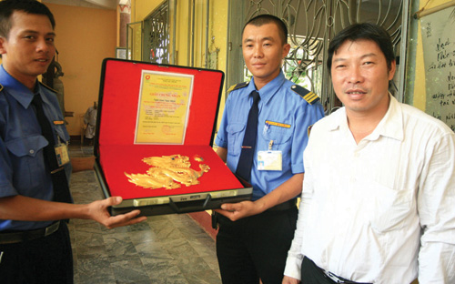Trần Văn Anh (bìa phải) bên con rồng bằng vàng thật dùng để gắn lên bức Thiên Long Việt đồ