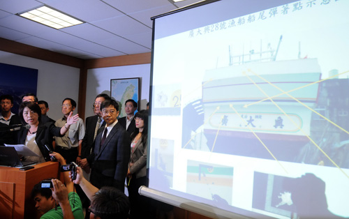 Bà Trần Văn Kỳ (trái) chỉ ra hình ảnh cho thấy những vết đạn mà tàu cá Đài Loan bị bắn