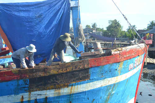 Ngư dân Trần Văn Quang huy động nhân công tu sửa lại tàu cá QNg 90917 TS để sớm đưa tàu ra khơi