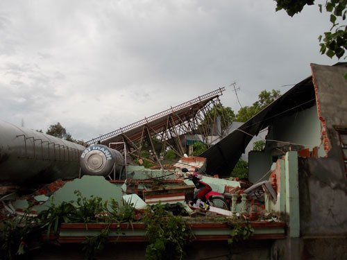 (TNO) Chiều ngày 15-5, trận mưa lớn kèm gió giật mạnh đã làm một giàn treo bảng quảng cáo đổ ập xuống, đè sập hai căn nhà nằm sát quốc lộ 13, huyện Chơn Thành, Bình Phước.1