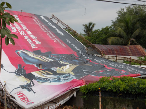 (TNO) Chiều ngày 15-5, trận mưa lớn kèm gió giật mạnh đã làm một giàn treo bảng quảng cáo đổ ập xuống, đè sập hai căn nhà nằm sát quốc lộ 13, huyện Chơn Thành, Bình Phước.