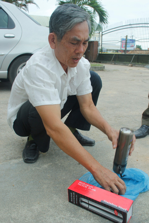 Ông Nguyễn Hồng Khoa, Đội trưởng Đội QLTT số 12 đang kiểm tra một phích nước chứa chất lạ