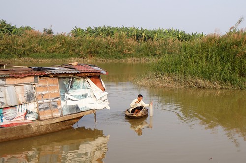 Ông Phú bơi thuyền, rải lưới đánh cá