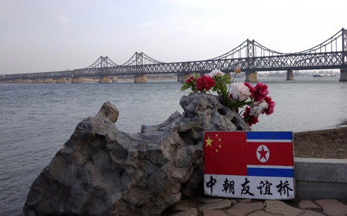 Tấm bảng in hình quốc kỳ Trung Quốc và Triều Tiên cạnh Cầu hữu nghị Trung-Triều dẫn sang Triều Tiên ở thành phố Đan Đông của Trung Quốc - Ảnh: AFP