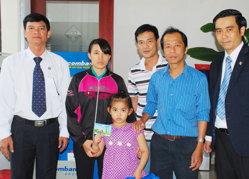 Đại diện Báo Thanh Niên và các nhà hảo tâm trao sổ tiết kiệm cho cháu Phan Thị Thùy Dương - Ảnh: Tấn Cư