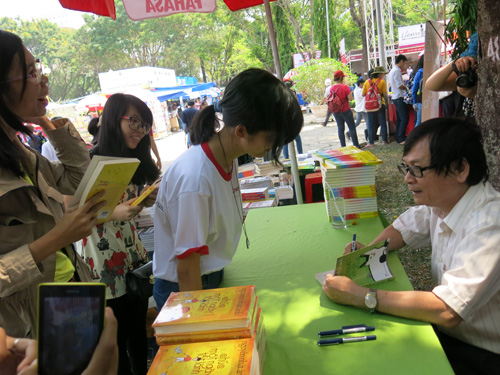 Nguyễn Nhật Ánh ký tặng sách tại hội chợ - Ảnh: H.Đ.N
