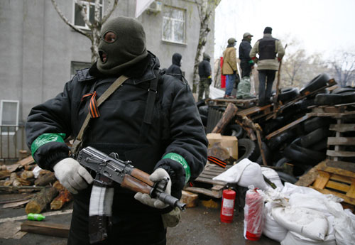 Một tay súng đứng kế hàng rào chướng ngại vật bên ngoài đồn cảnh sát ở thành phố Slavyansk  - Ảnh: Reuters
