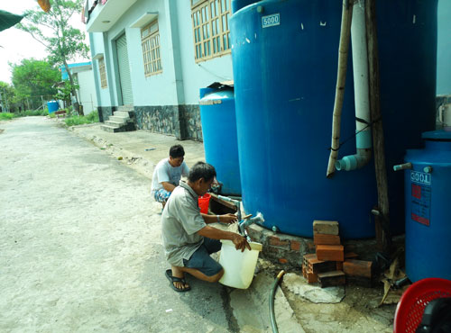 Bà con khu dân cư Dân An phải xách từng xô nước sạch từ các bồn chứa về dùng - Ảnh: Thanh Đông