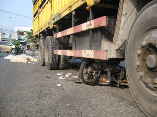 Hiện trường vụ tai nạn và xe máy bị cán nát dưới gầm xe tải