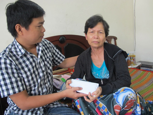 Đại diện Báo Thanh Niên trao tiền của bạn đọc và thăm hỏi sức khỏe mẹ thuyền trưởng Lê Trung Thành - Ảnh: Công Sơn