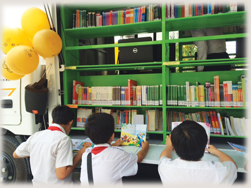 Học sinh Trường THCS Lê Minh Xuân bên thư viện sách di động Bánh xe tri thức 
