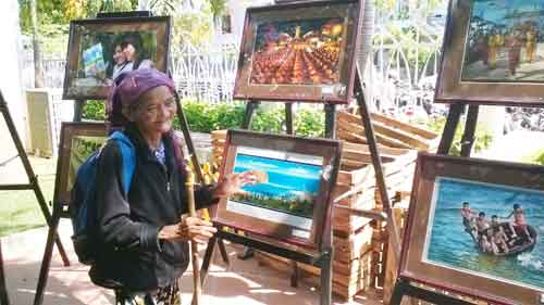 Một cụ bà người dân tộc thiểu số tham quan triển lãm ảnh