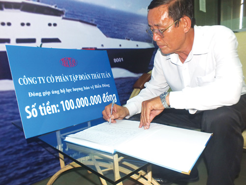 Ông Hồ Văn Anh, Chủ tịch Công đoàn cơ sở Công ty CP Tập đoàn Thái Tuấn, đại diện công ty ủng hộ 100 triệu đồng và ghi ý kiến vào sổ ủng hộ các lực lượng bảo vệ biển Đông - Ảnh: Hải Nam