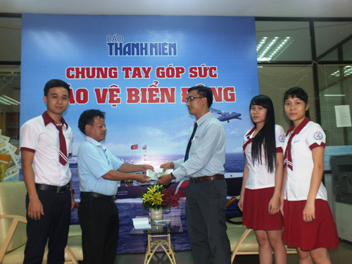 Thầy Bùi Gia Hiếu và các em học sinh Trường THPT Nhân Việt (TP.HCM) trao tiền ủng hộ lực lượng bảo vệ biển Đông cho đại diện Báo Thanh Niên - Ảnh: H.N