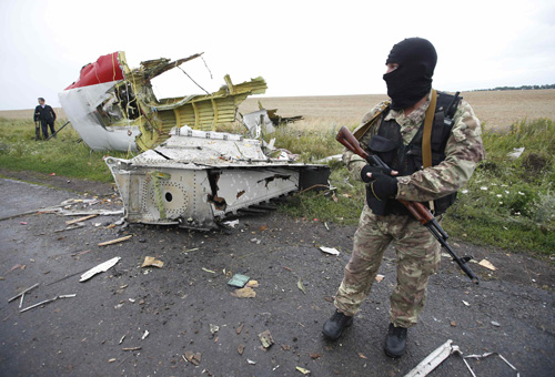 Một tay súng nổi dậy ở miền đông Ukraine đứng gác địa điểm có mảnh vỡ máy bay - Ảnh: Reuters