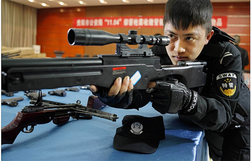 Cảnh sát Trung Quốc thử một khẩu súng mà tịch thu được trong một chiến dịch truy quét - Ảnh: AFP