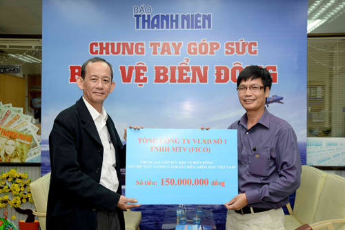 Ông Lương Cao Núi (bên phải) trao tiền cho đại diện Báo Thanh Niên - Ảnh: Diệp Đức Minh