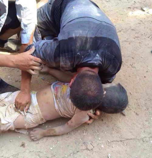 Một người cha vật vã bên thi thể con tại thành phố Chiêu Thông - Ảnh: AFP