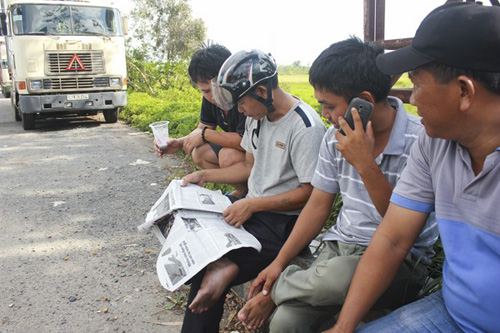 Nhóm tài xế ngồi đọc thông tin vụ xe ùn ứ tại cửa khẩu Mộc Bài