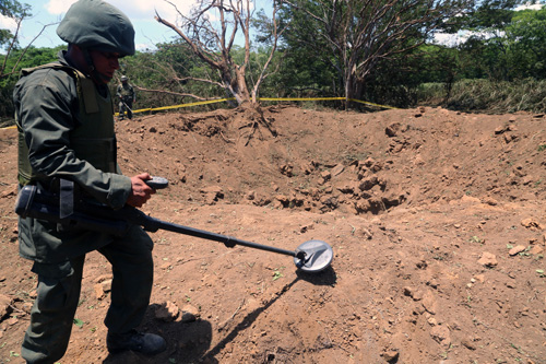 Một binh sĩ xem xét cái hố xuất hiện sau vụ nổ - Ảnh: AFP