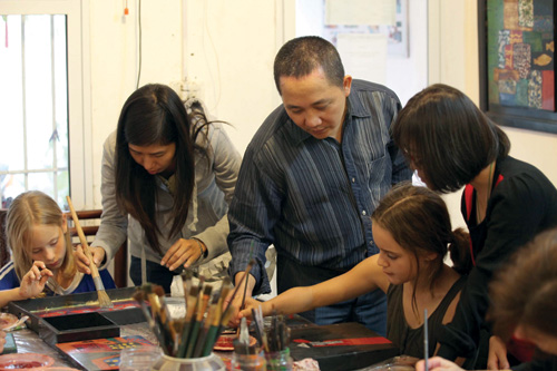 Hoạ sĩ Trần Anh Tuấn hướng dẫn các học viên người nước ngoài trong lớp học sơn mài - Ảnh: Ngọc Thắng