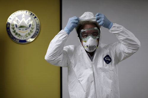 Một chuyên gia chỉ cách mang bộ bảo hộ được dùng khi tiếp xúc bệnh nhân Ebola - Ảnh: Reuters