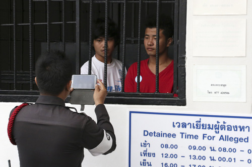 Một cảnh sát chụp hình hai công nhân người Myanmar Win Zaw Htun (trái) và Zaw Lin bị cáo buộc giết hai du khách người Anh tại tòa án ngày 4.10 - Ảnh: Reuters