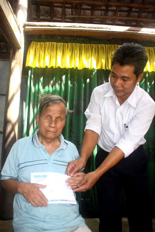 Ông Bùi Xuân Giang, Chủ tịch UBND xã Hải Tân (phải), trao tiền của bạn đọc giúp ông Vân