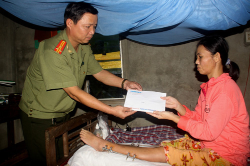 Thượng tá Đào Văn Khâm, Phó trưởng công an H.Hải Lăng trao số tiền do bạn đọc giúp đỡ chị Lan