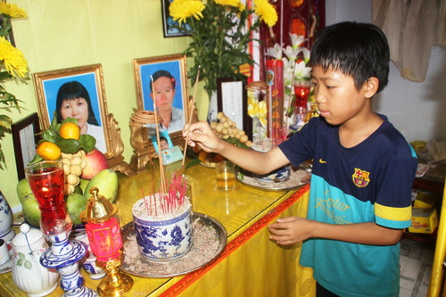 Bé Nguyễn Nguyên Ngọc đang thắp hương cho cha mẹ - Ảnh: H.S
