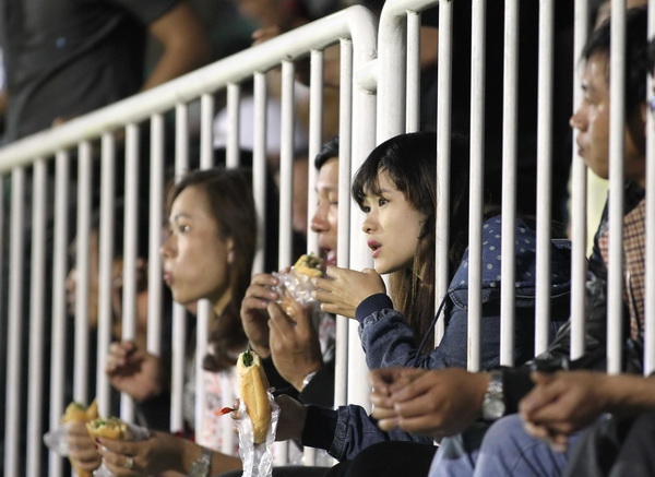 Một fan nữ thò đầu qua hàng rào kiểm soát ở trận HAGL thắng S.Khánh Hòa BVN 4-2. Điểm đặc biệt của sân Pleiku so với các sân khác trên cả nước là tỷ lệ phụ nữ và trẻ em vào sân rất cao