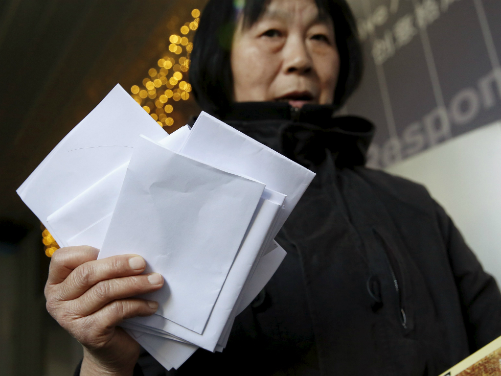Một phụ nữ cầm đơn kiện của bà và nhiều người khác tại văn phòng hãng Malaysia Airlines ở Bắc Kinh, Trung Quốc - Ảnh: Reuters