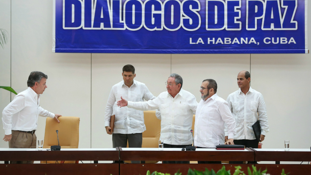 Chủ tịch Cuba, Raul Castro (giữa) và lãnh đạo phe nổi dậy Rodrigo Londono (phải) chờ bắt tay với Tổng thống Colombia, Juan Manuel Santos (trái) - Ảnh: Reuters