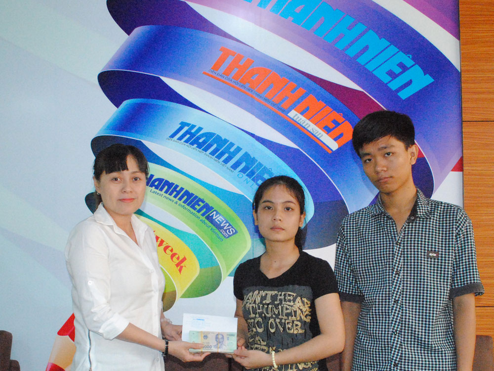 Đại diện Báo Thanh Niên (bìa trái) trao tiền bạn đọc giúp 2 sinh viên nghèo vượt khó - Ảnh: Bùi Chiến