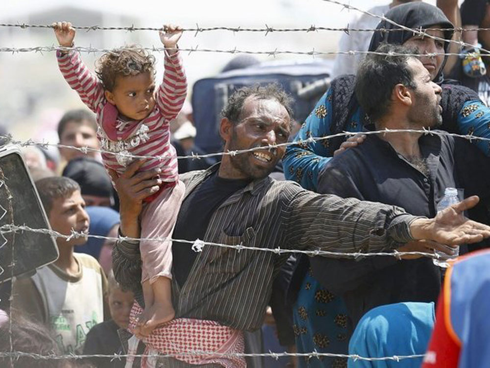 Người tị nạn Syria phía sau hàng rào biên giới chờ vào Thổ Nhĩ Kỳ hồi tháng 6.2015 - Ảnh: Reuters