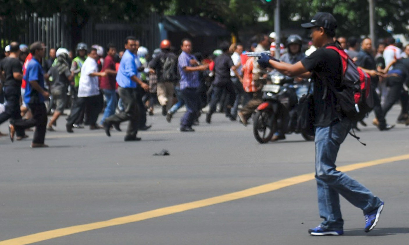 Một kẻ tấn công chĩa súng vào cảnh sát và đám đông ở Jakarta - Ảnh: Reuters/Tân Hoa xã