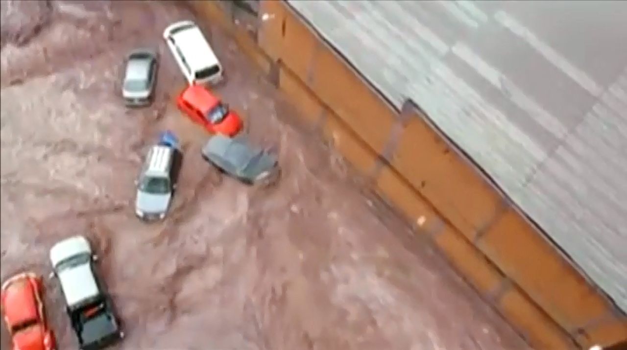 Lũ tràn vào thành phố và nước chảy xiết tới mức cuốn trôi hàng loạt xe hơi - Ảnh: Chụp từ clip