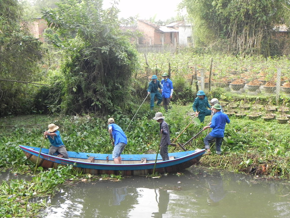 Thanh niên thu gom rác trên dòng sông ở khu vực Cẩm Văn, phường Nhơn Hưng