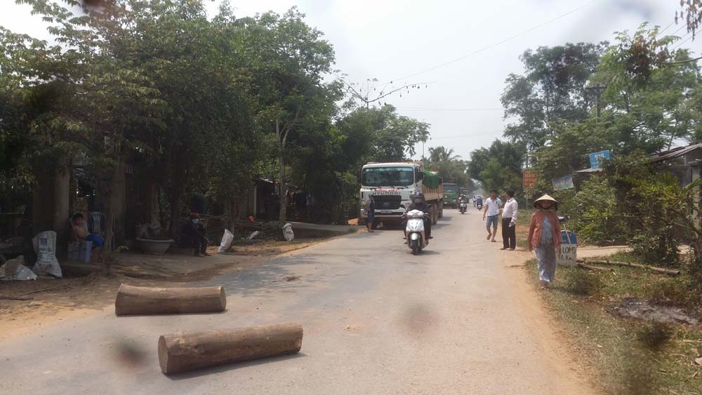 Bức xúc xe tải chở đất gây bụi, người dân xã Hành Minh dùng cây gỗ chặn ngang tuyến tỉnh lộ 624 - Ảnh: Hiển Cừ