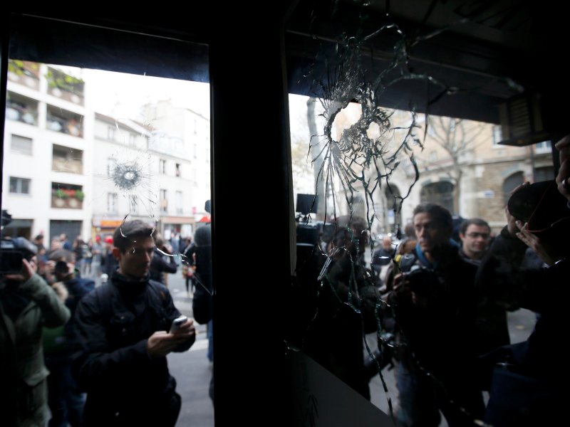 Các phóng viên đứng bên ngoài một ngôi nhà có những vết đạn từ một trong những vụ tấn công khủng bố đẫm máu nhắm vào dân thường ở thủ đô Paris, Pháp đêm 13.11.2015 - Ảnh: Reuters
